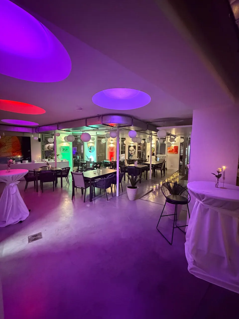 Die Markthalle für eine Feier in lila Licht, weiß eingedeckte Tische