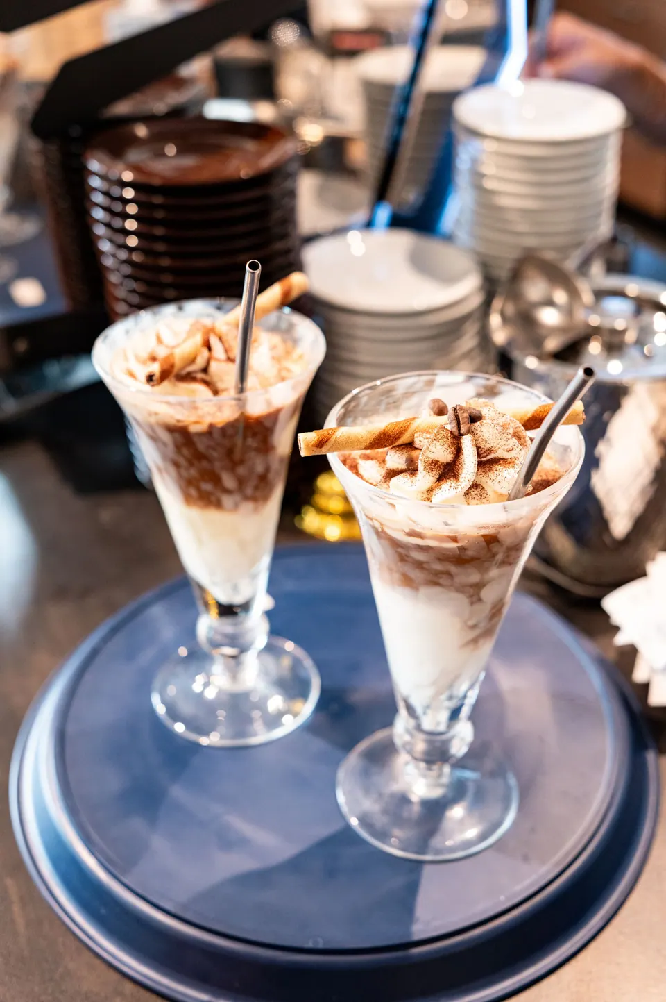 Zwei Eisbecher mit Waffel und Schokoladensauce auf einem Tablett an der Theke